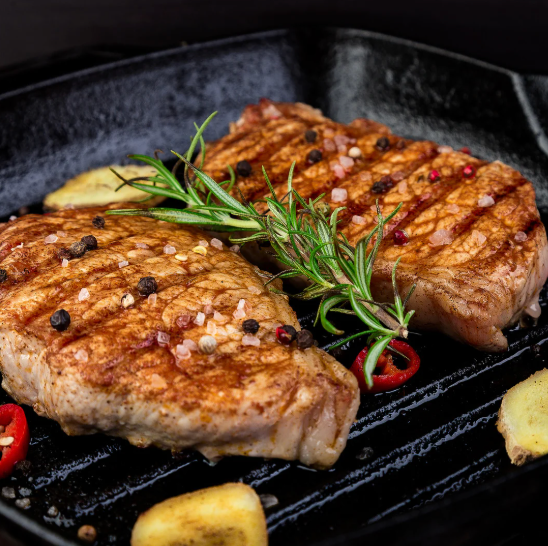 Grilled meat with herbs and spices on a black grill pan