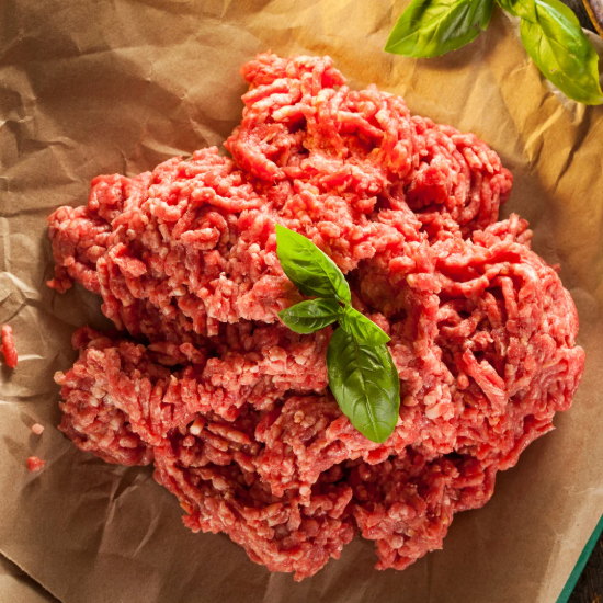 Raw ground meat with basil leaves on brown paper